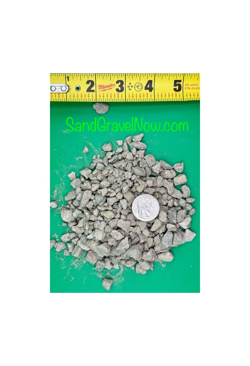 Small gray 3/8 inch crushed gravel pieces on a green board with a quarter and a tape measure for scale.